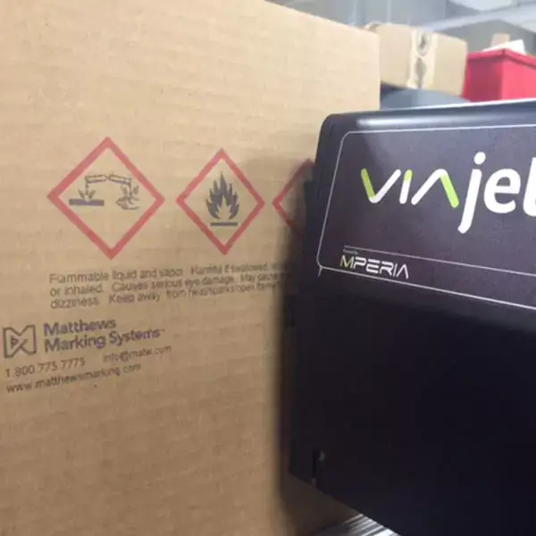 Varningssymboler och säkerhetstext tryckta på en wellpappkartong