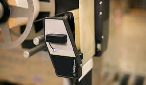 Närbild på en automatisk etikettapplikator av A-serien från Matthews Marking Systems som används för slitstark inom industriell förpackningsverksamhet.