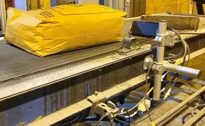Gula industriförpackningar med tryckta identifieringskoder som transporteras längs ett transportband i en tillverkningsanläggning.